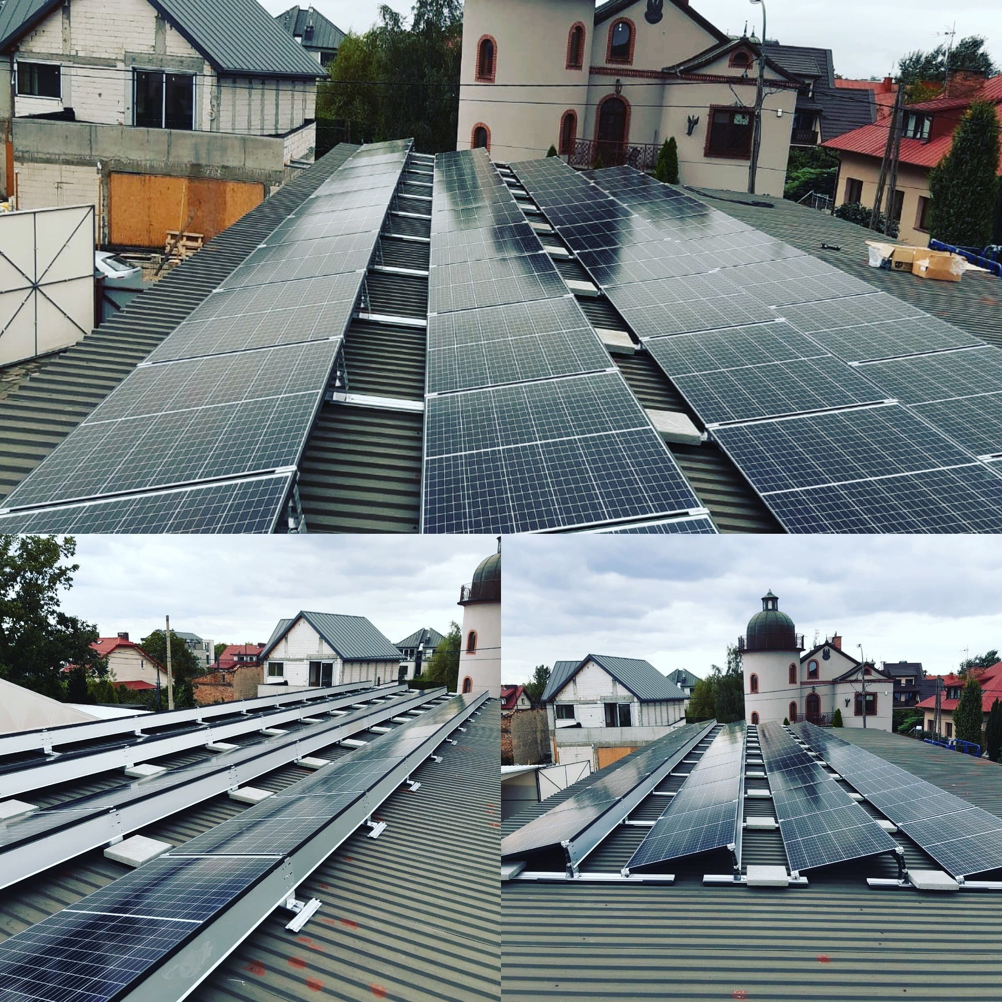 Instalacja paneli słonecznych na dachu z blachy trapezowej, widok z góry na tle zabudowy miejskiej z charakterystyczną wieżą.