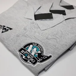 Stos szarych koszulek polo z logo 'Wake Zone Stawiki' z Sosnowca, widoczne metki.