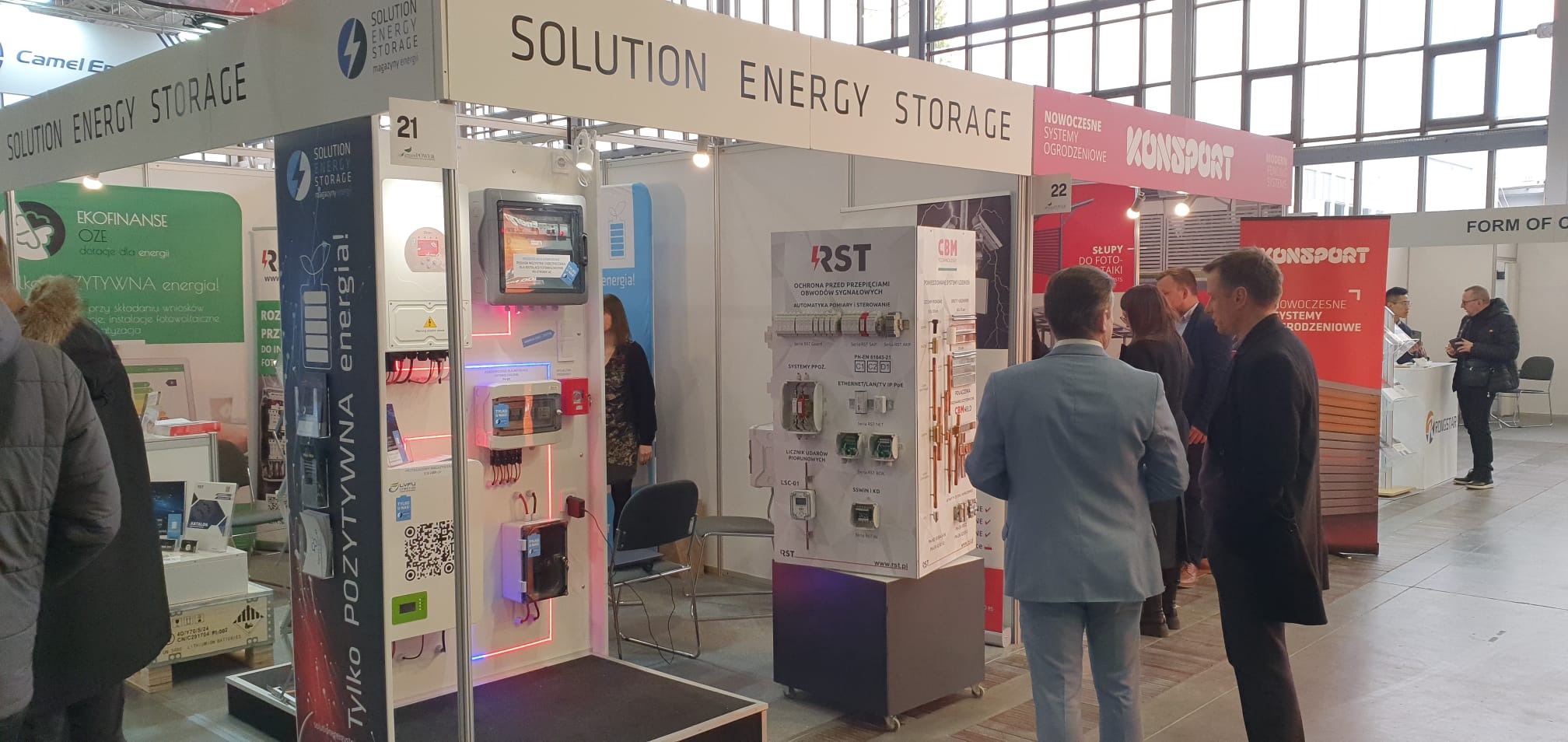 Stoisko targowe firmy Solution Energy Storage z ekspozycją systemów magazynowania energii i osprzętu elektrycznego, prezentowane podczas targów branżowych, z widocznymi osobami zwiedzającymi.