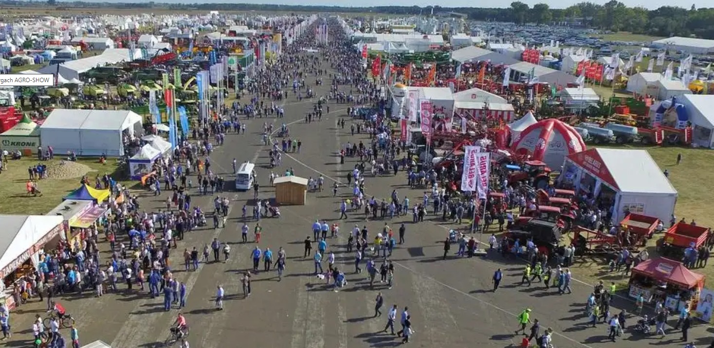 Panoramiczny widok z lotu ptaka na targi rolnicze Agro-Show z tłumem ludzi, maszynami rolniczymi i stoiskami wystawienniczymi.