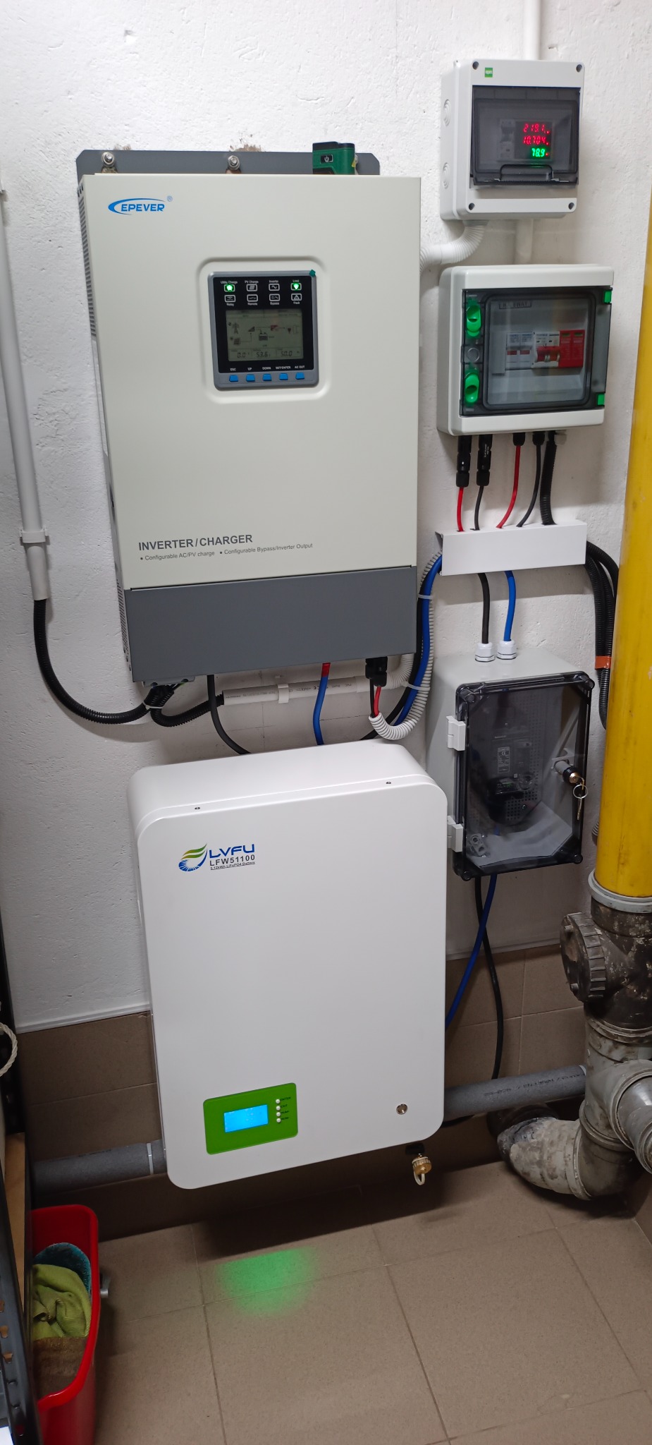 Zamontowany inwerter/ładowarka EPEVER i magazyn energii LVFU LFW51100 na ścianie, widoczne również skrzynki z bezpiecznikami i okablowanie.
