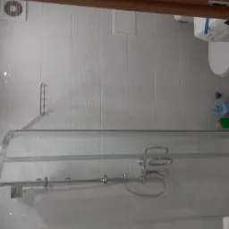 Wykończona łazienka z kabiną prysznicową, pralką Bosch i białymi płytkami z delikatnym wzorem, widoczna wentylacja i akcesoria łazienkowe.