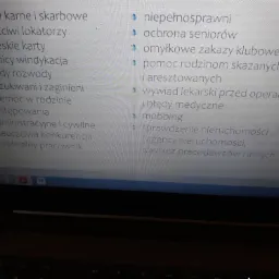 Ekran laptopa wyświetlający listę spraw prawnych, w tym sprawy karne, rozwody, windykacja długów, mobbing i inne. Lista jest częściowo widoczna, z widocznymi ikonami list i tekstem w kolorze białym...