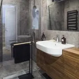 Nowoczesna łazienka z szarą mozaiką na ścianie prysznica, białą umywalką wpuszczoną w drewniany blat, czarnym grzejnikiem drabinkowym i szklaną kabiną prysznicową.