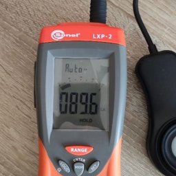 VK ELEKTRO SPÓŁKA Z OGRANICZONĄ ODPOWIEDZIALNOŚCIĄ - Miernik natężenia światła Sonel LXP-2 z wyświetlaczem wskazującym 89.6 Lx, leżący na drewnianej powierzchni. Widoczny czujnik światła na kablu.