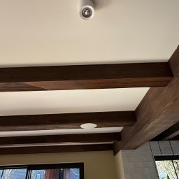 ELCOM - INSTALACJE ELEKTRYCZNE - Wnętrze z drewnianymi belkami stropowymi i okrągłym, białym reflektorem sufitowym