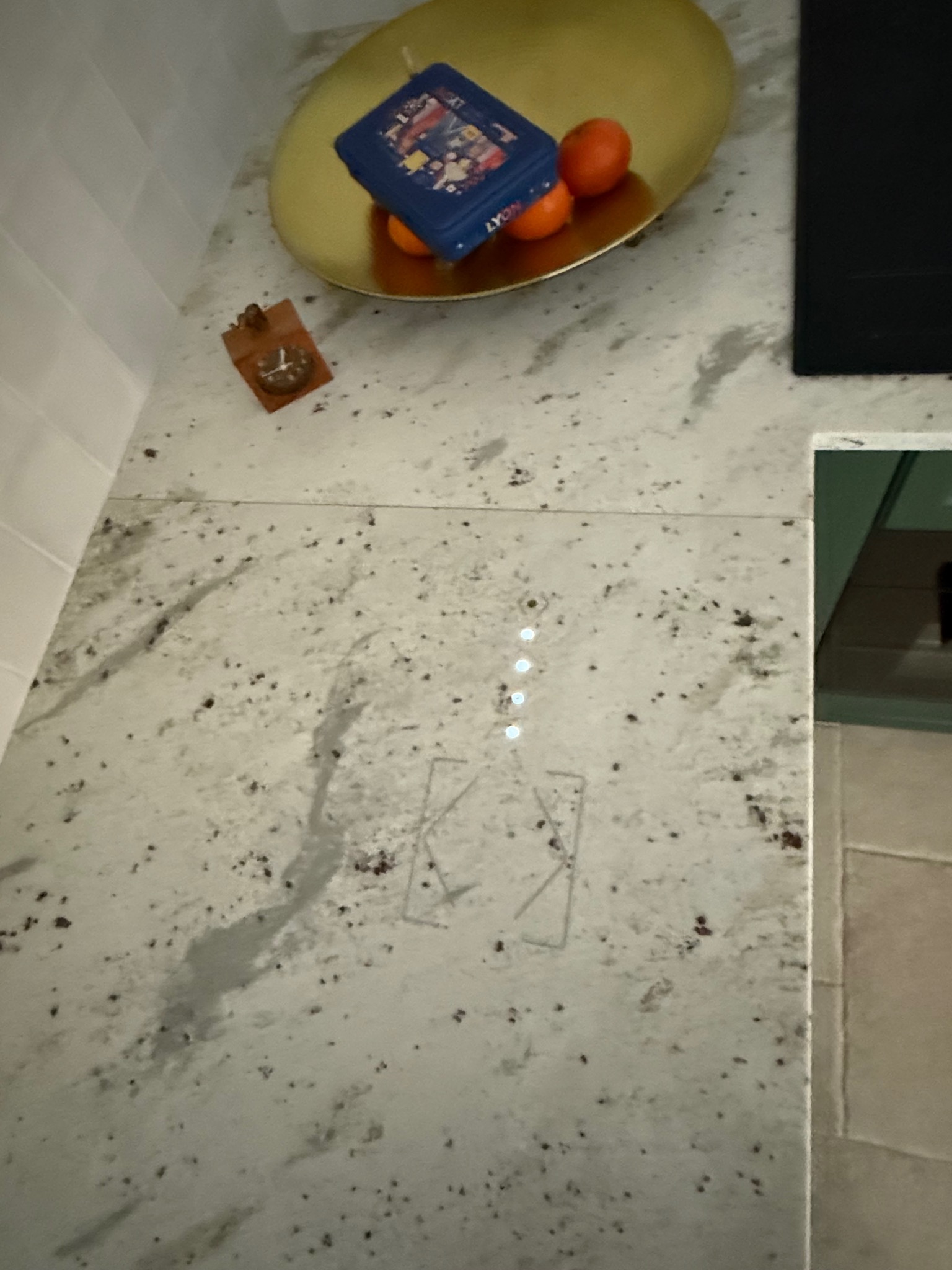 Blat kuchenny z wbudowaną płytą indukcyjną z dotykowym panelem sterowania, na blacie ozdobna misa z owocami i pudełkiem.