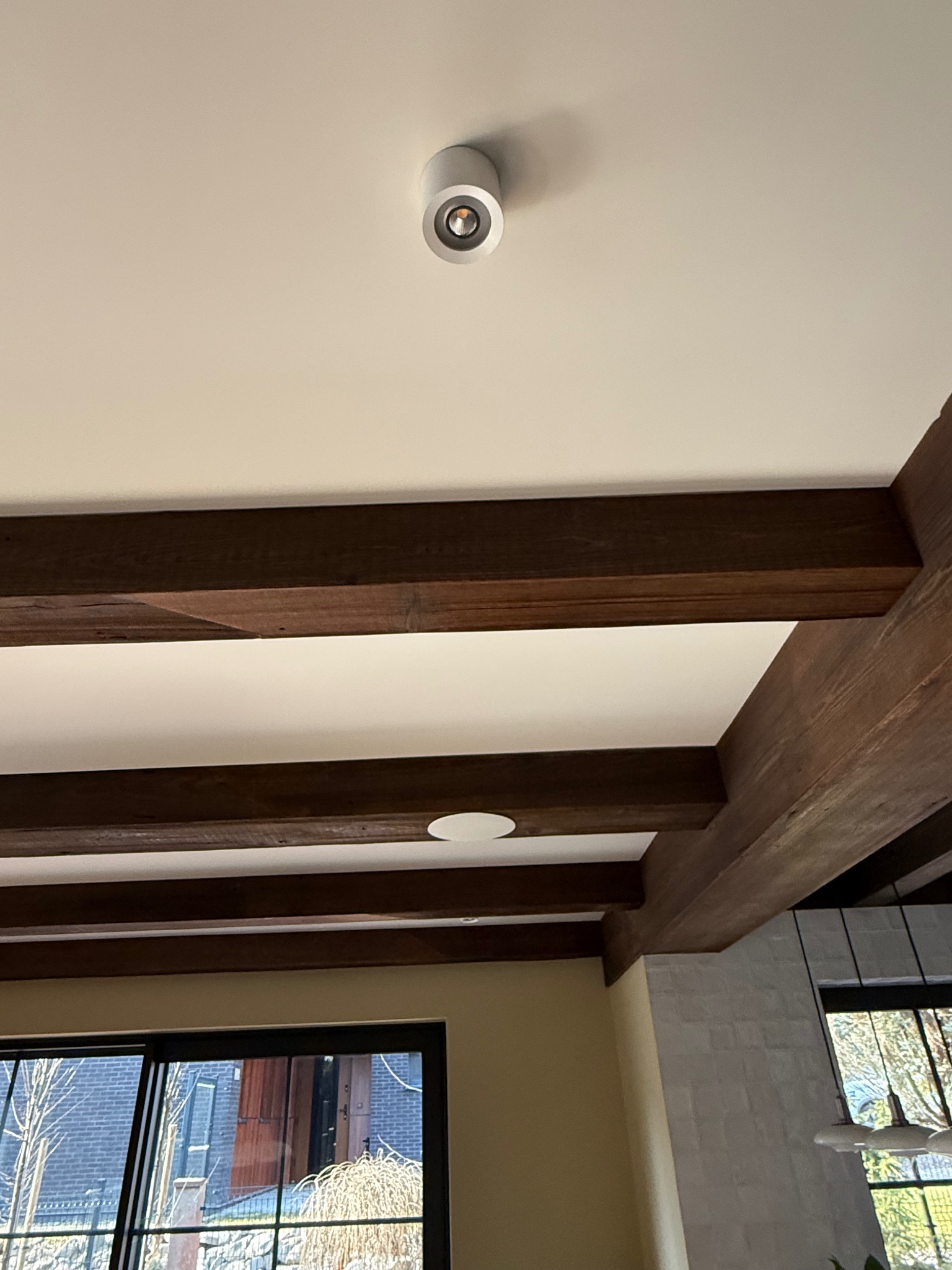 Wnętrze z drewnianymi belkami stropowymi i okrągłym, białym reflektorem sufitowym