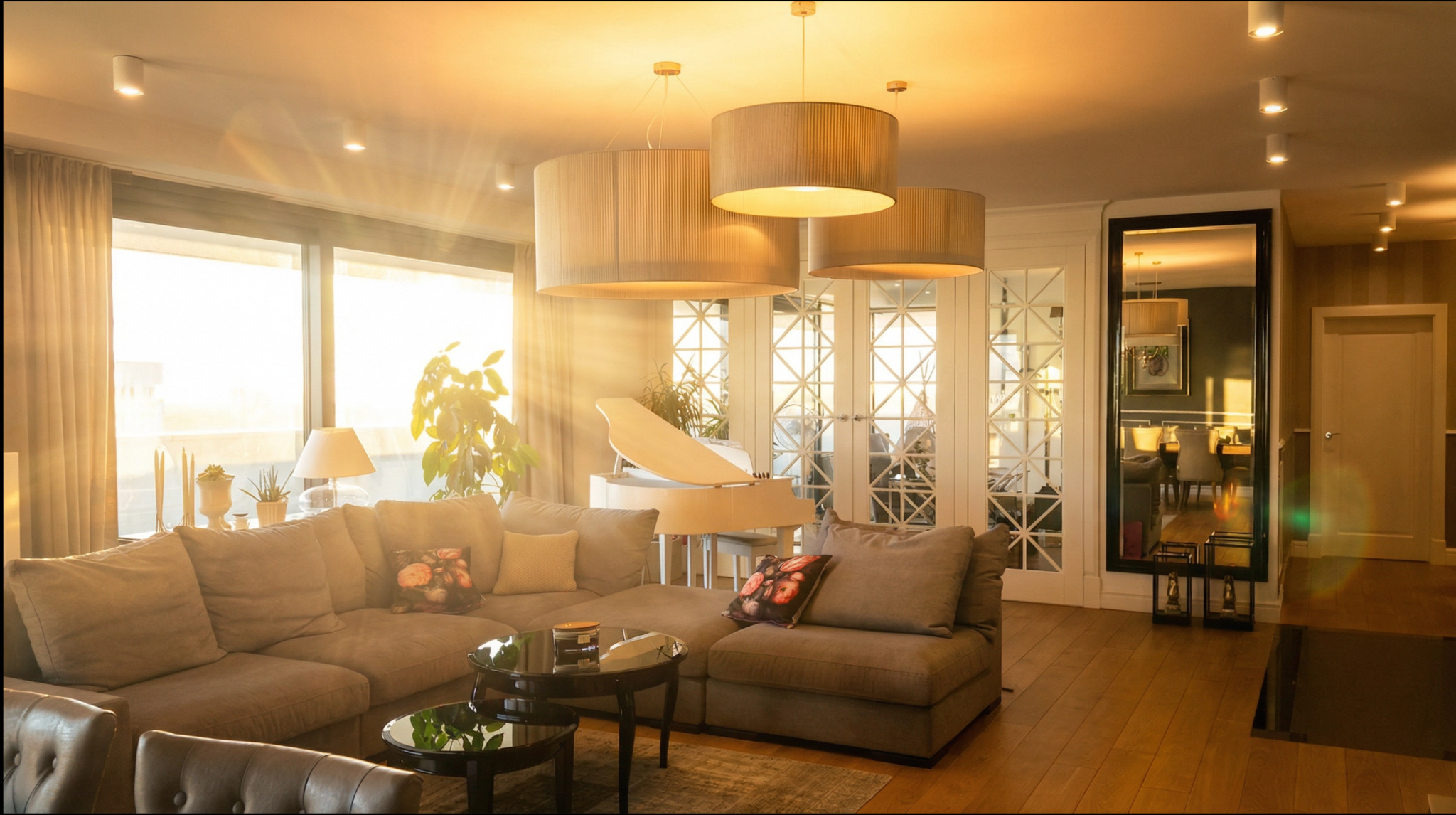 Jasne wnętrze salonu z dużym oknem, szarą sofą, fortepianem i okrągłymi lampami. Promienie słoneczne wpadają do pomieszczenia, oświetlając parkiet.