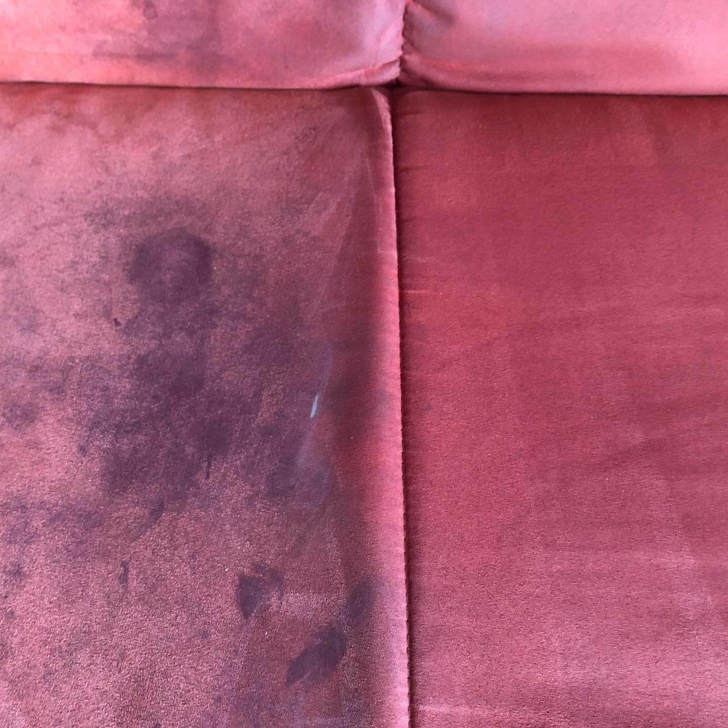 Czerwona welurowa kanapa: po lewej stronie widoczne ciemne plamy i zabrudzenia, po prawej czysta powierzchnia po zabiegu czyszczenia.