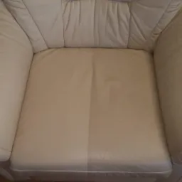 Beżowy fotel skórzany, widoczna różnica w czystości po lewej i prawej stronie siedziska, ukazująca efekt czyszczenia.