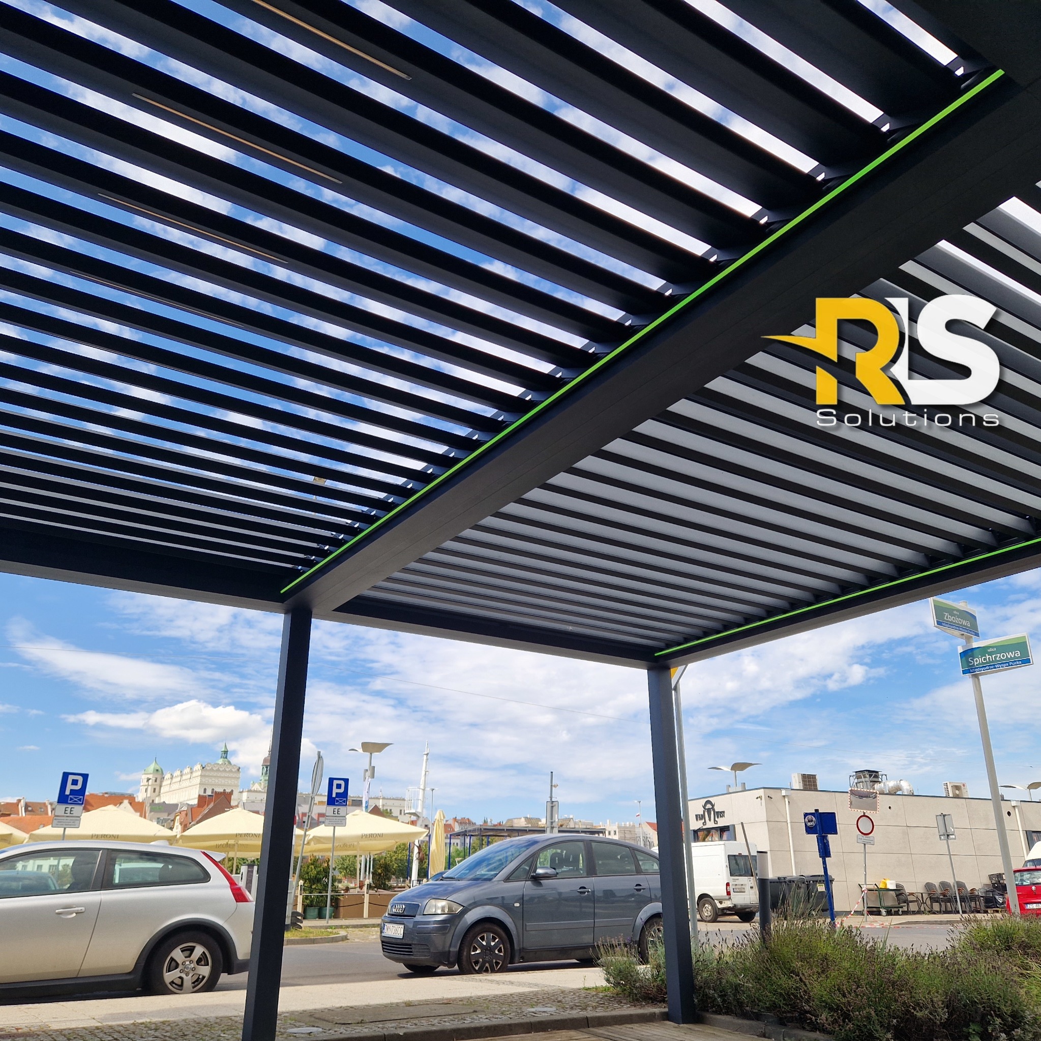 Nowoczesna pergola metalowa z logo firmy RS Solutions w Złocieńcu, widok od dołu na konstrukcję i niebo, z elementami otoczenia miejskiego w tle.