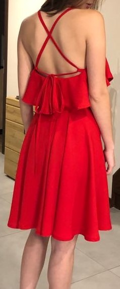 Czerwona, krótka sukienka z falbanką i skrzyżowanymi ramiączkami na plecach, widok z tyłu.