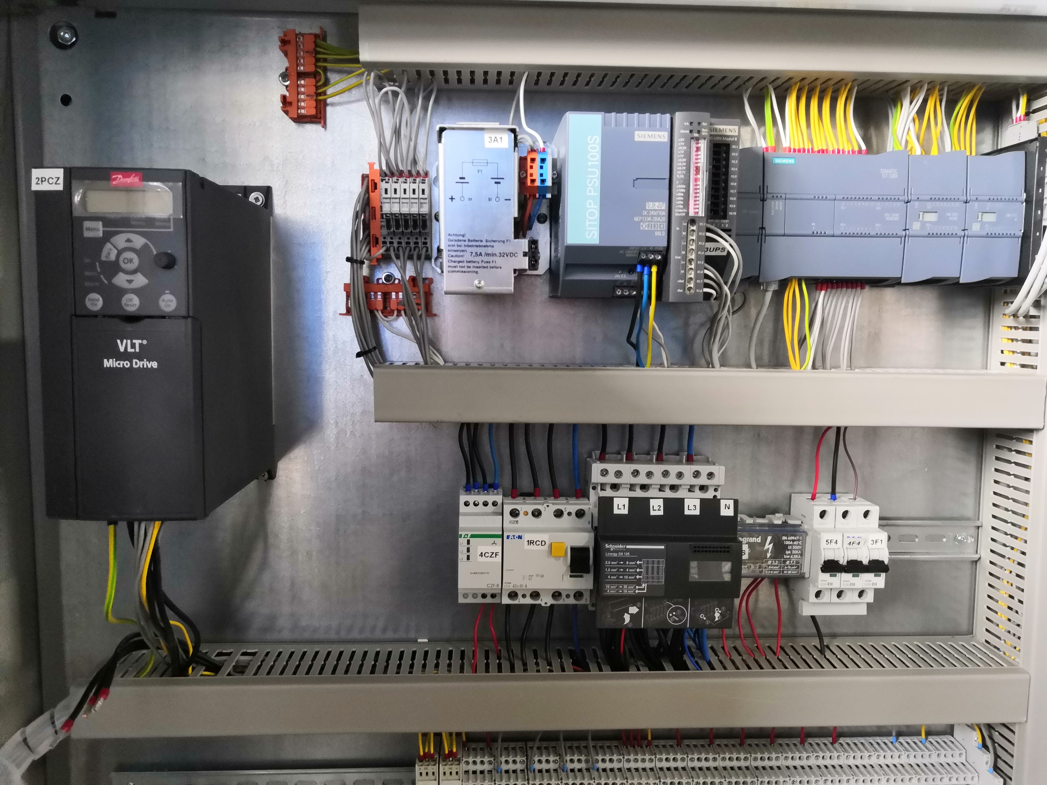 Wnętrze szafy sterowniczej z zainstalowanym falownikiem Danfoss VLT Micro Drive, zasilaczem Siemens SITOP PSU100S, sterownikiem Siemens SIMATIC S7-1200, różnymi zabezpieczeniami i przekaźnikami...