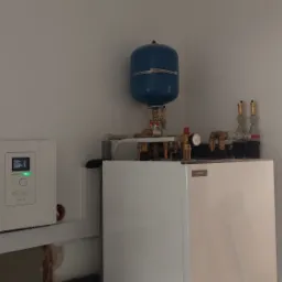 Biała pompa ciepła NIBE z niebieskim zbiornikiem wyrównawczym, widoczne rury miedziane i manometr, montaż w surowym wnętrzu z widocznym otworem w ścianie i fragmentem garażu