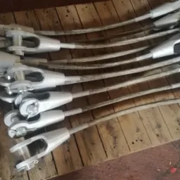 Szare stalowe liny z końcówkami widełkowymi ułożone równolegle na drewnianej palecie.