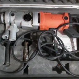 Wiertarka udarowa Carat w szarej walizce z miejscem na akcesoria, widoczny przewód zasilający oraz wiertło.