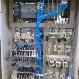 Otwarta szafa sterownicza z modułami PLC Siemens, regulatorami ciśnienia i pneumatycznymi elementami wykonawczymi połączonymi niebieskimi przewodami pneumatycznymi.