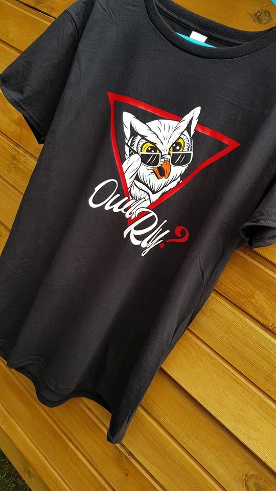 Czarna koszulka z nadrukiem sowy w okularach, umieszczonej w czerwonym trójkącie, z napisem 'Owl Rly?' na tle drewnianej powierzchni.