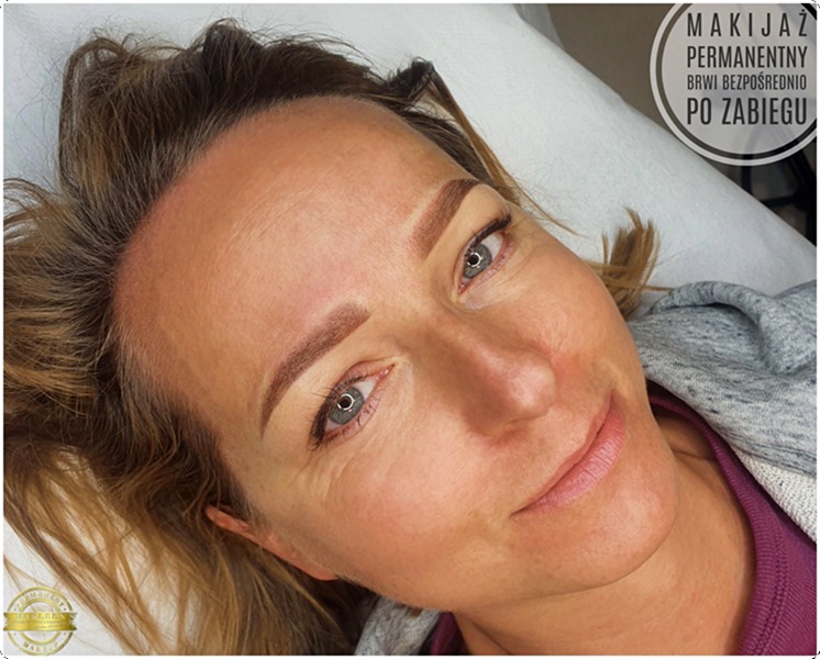Kobieta po zabiegu makijażu permanentnego brwi, widoczne świeżo wykonane, symetryczne brwi w odcieniu brązu, leżąca na białym podkładzie.