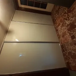 Ściana z płyt kartonowo-gipsowych w trakcie prac wykończeniowych w Pile, widoczna także ściana wyłożona mozaiką z kamienia.