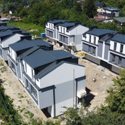 PHU Papierowski - Nowoczesne, dwukondygnacyjne domy szeregowe z szarymi dachami i elewacją w odcieniach szarości, otoczone zielenią. Widok z góry ukazuje detale wykończenia.