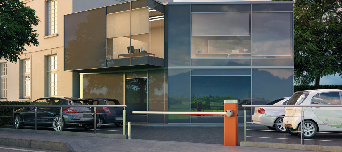 Szlaban automatyczny w pozycji otwartej przed nowoczesnym budynkiem biurowym z zaparkowanymi samochodami.