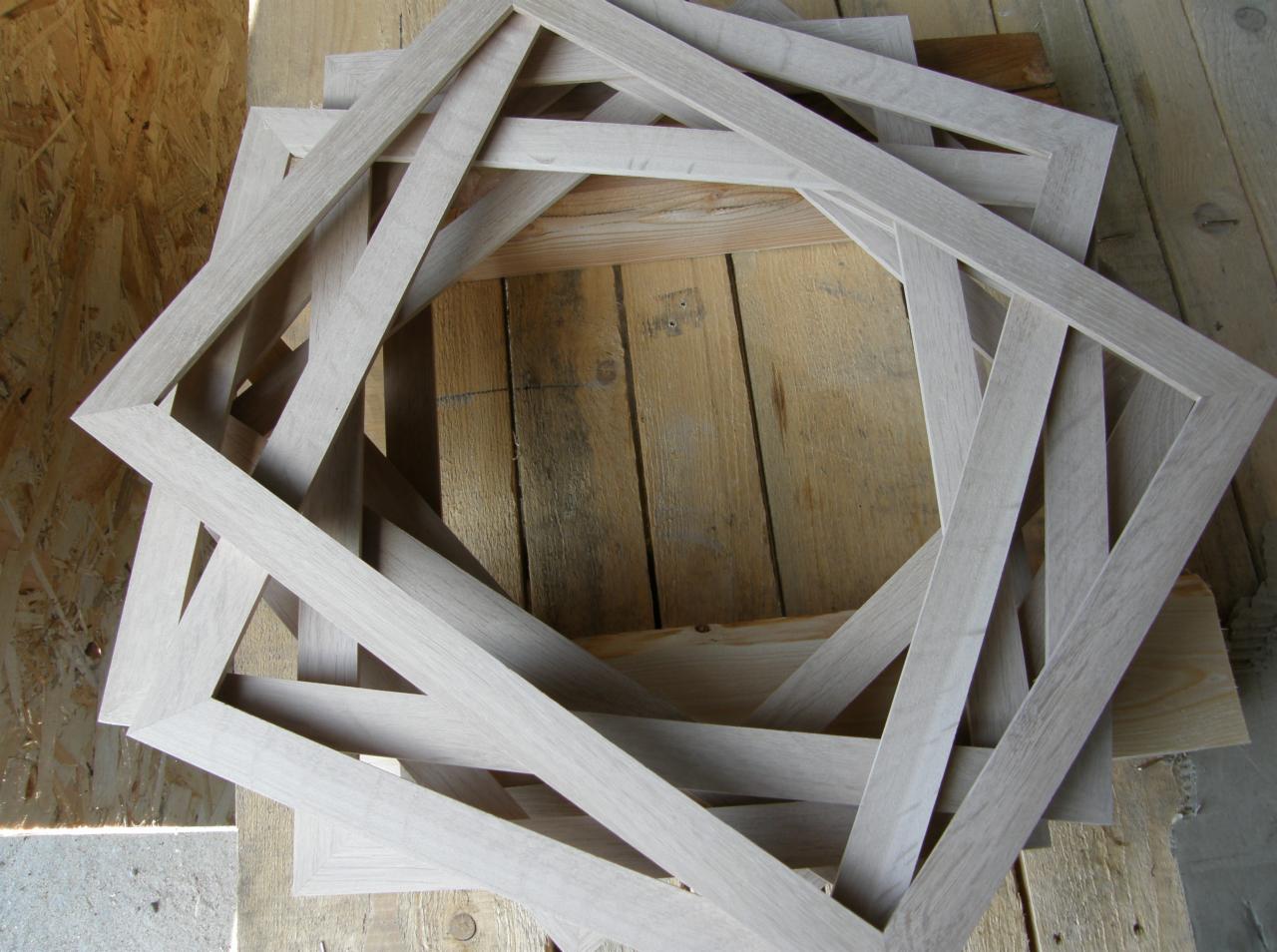 Stos drewnianych, surowych ramek o kwadratowym kształcie, ułożonych na drewnianej powierzchni.