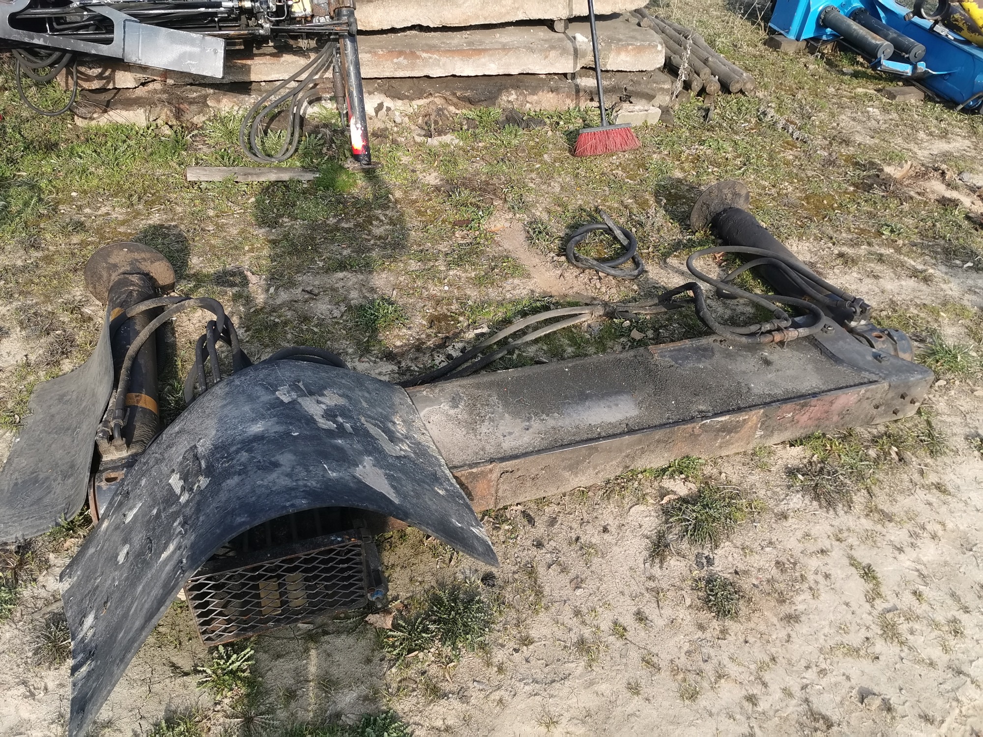 Części maszyny budowlanej, prawdopodobnie do wyburzeń, leżą na ziemi w Przeworsku, widoczne ślady użytkowania i zabrudzenia.