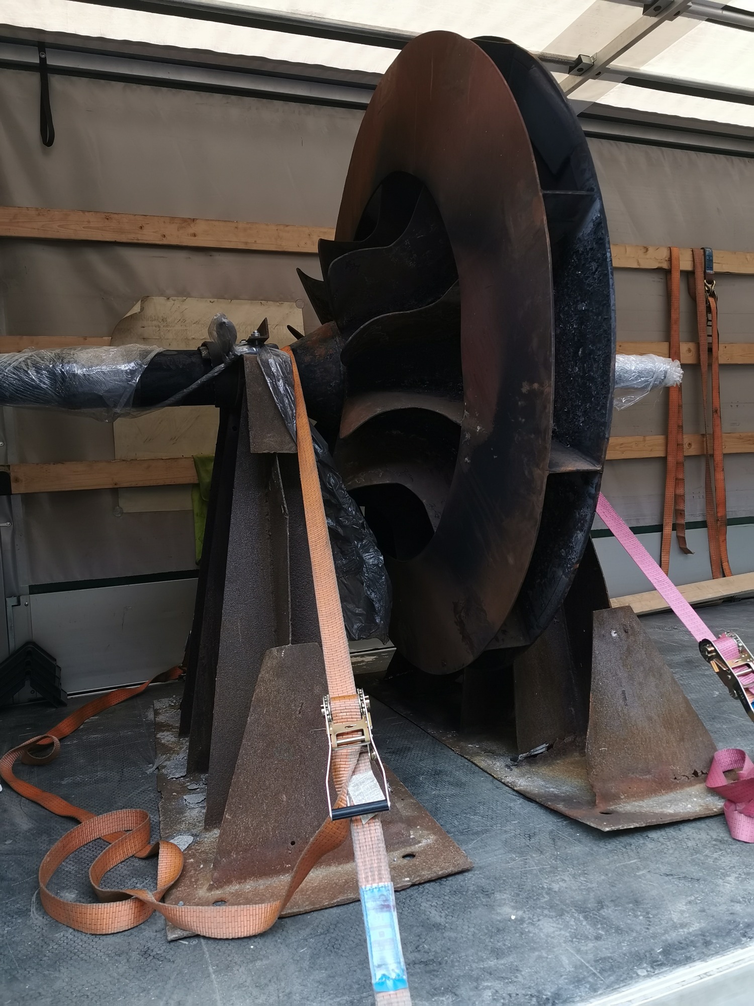 Duży, przemysłowy wentylator promieniowy zabezpieczony pasami transportowymi wewnątrz przestrzeni ładunkowej busa.