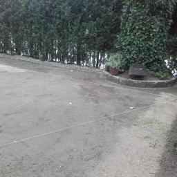 OGRODY Marta Góźdź - Przygotowany teren pod trawnik z wytyczonymi sznurkami, widoczne obrzeża z kamienia i roślinność w tle.