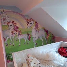 Usługi ogólnobudowlane Jacek Michorzewski - Pokój dziecięcy z tapetą w jednorożce i tęczę, łóżko zabezpieczone folią malarską, widoczne akcesoria do pokoju.