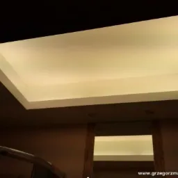 Oświetlenie sufitowe wpuszczone w ramę, widok z dołu, ciepłe światło.