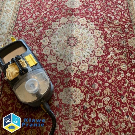Częściowo wyprany, czerwony dywan orientalny z maszyną czyszczącą; widoczna różnica w kolorze i czystości wzoru, co demonstruje efektywność procesu prania.
