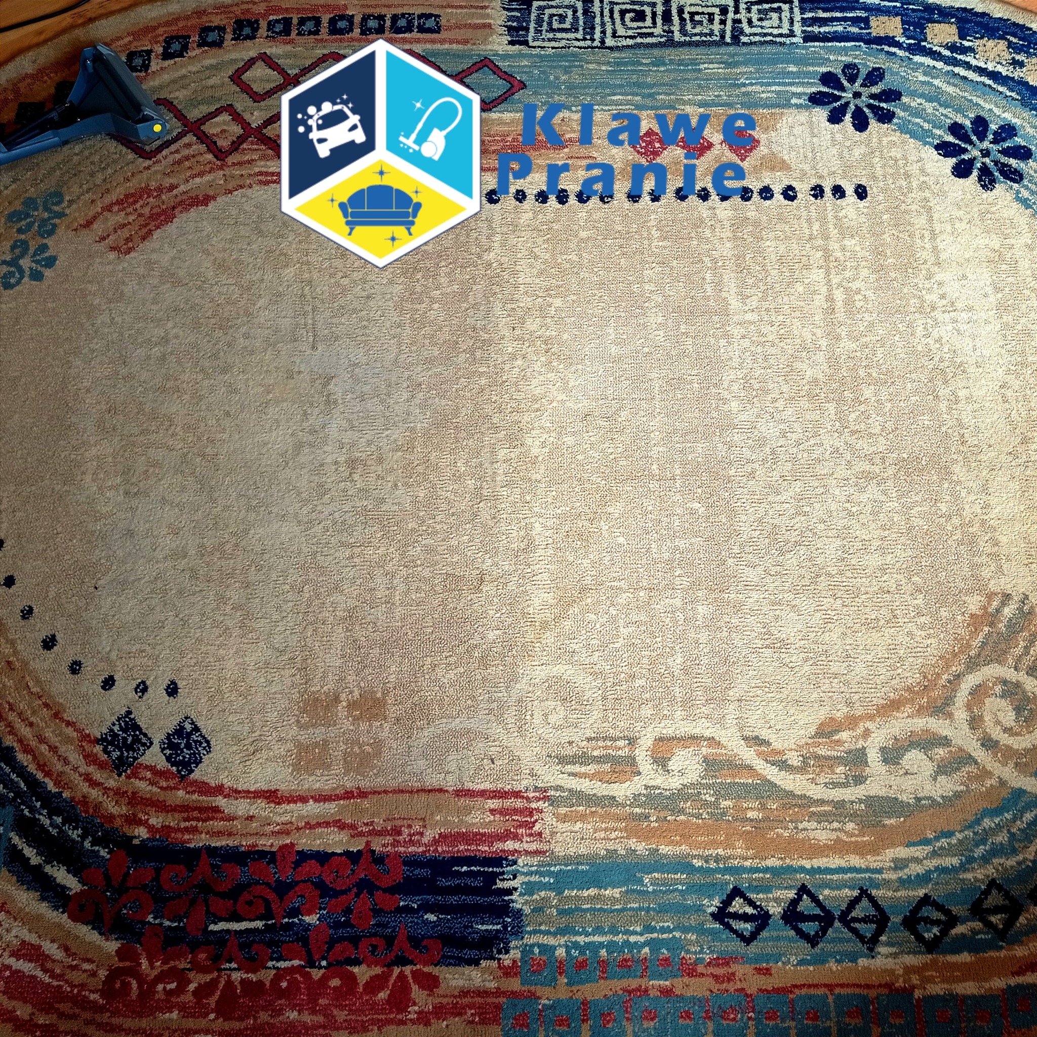 Owalny, wzorzysty dywan po czyszczeniu, widoczny fragment odkurzacza. Centralna część dywanu jaśniejsza, co sugeruje świeże pranie.