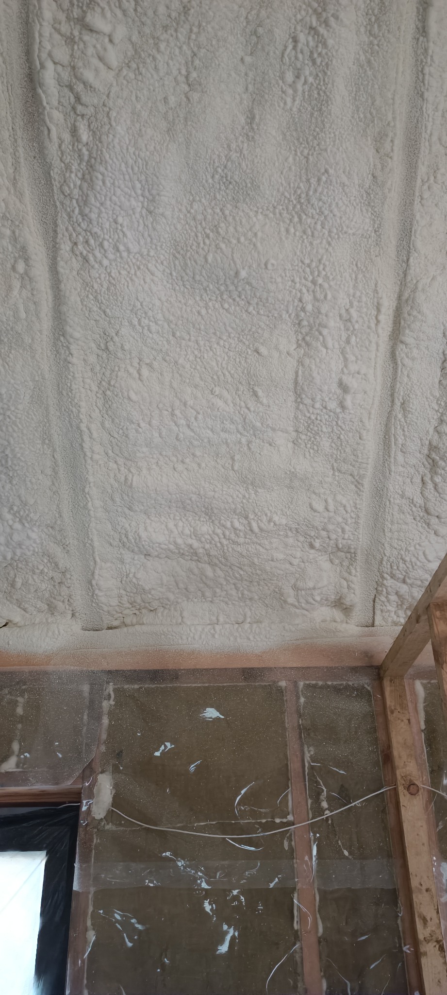 Poddasze z widoczną strukturą natryśniętej pianki PUR, drewniany szkielet konstrukcyjny, folia ochronna na ścianie.