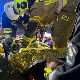 PROLIFE Sebastian Wrona - Ratownicy OSP udzielają pomocy poszkodowanemu, przykrytemu złotą folią termiczną, w warunkach nocnych podczas akcji ratunkowej.