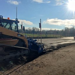 GAL-Bruk - Żółta ładowarka gąsienicowa CAT 287B z frezarką do asfaltu przygotowuje podłoże pod budowę, widoczne ślady gąsienic i świeżo sfrezowany teren.