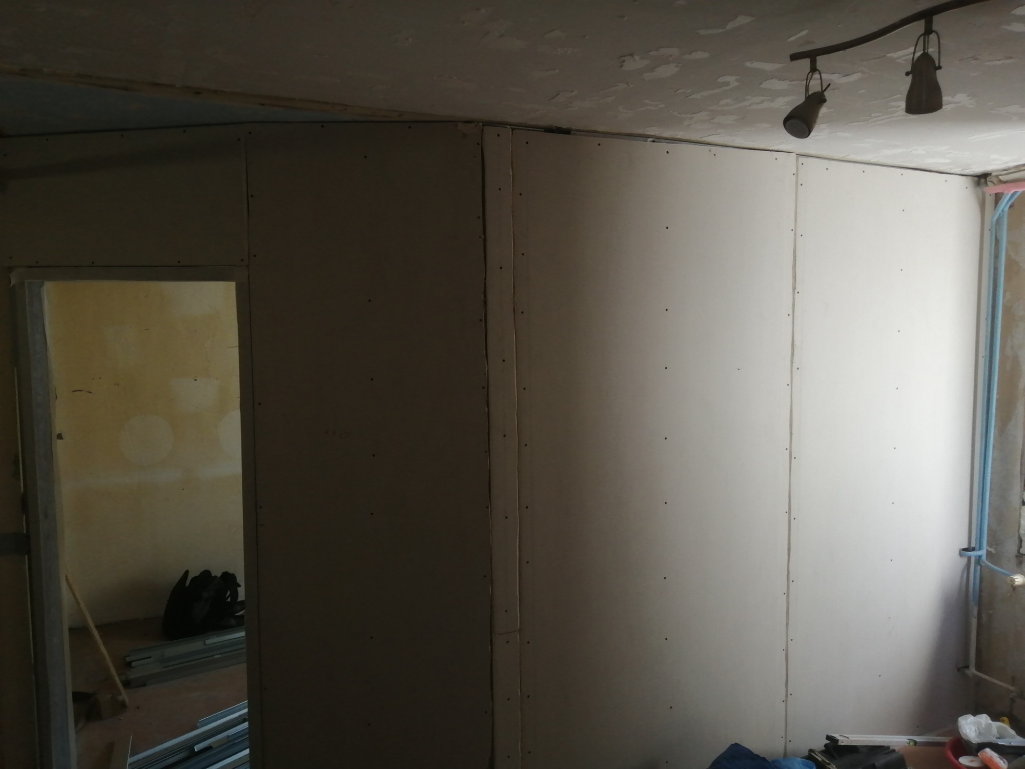 Montaż płyt karton gips na ścianie w trakcie remontu, widoczne profile i narzędzia w tle, surowy stan wykończenia.