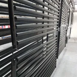 Czarne, metalowe rury po obróbce, zawieszone na wieszakach w hali produkcyjnej w Grochowie Szlacheckim, gotowe do dalszej obróbki lub transportu.