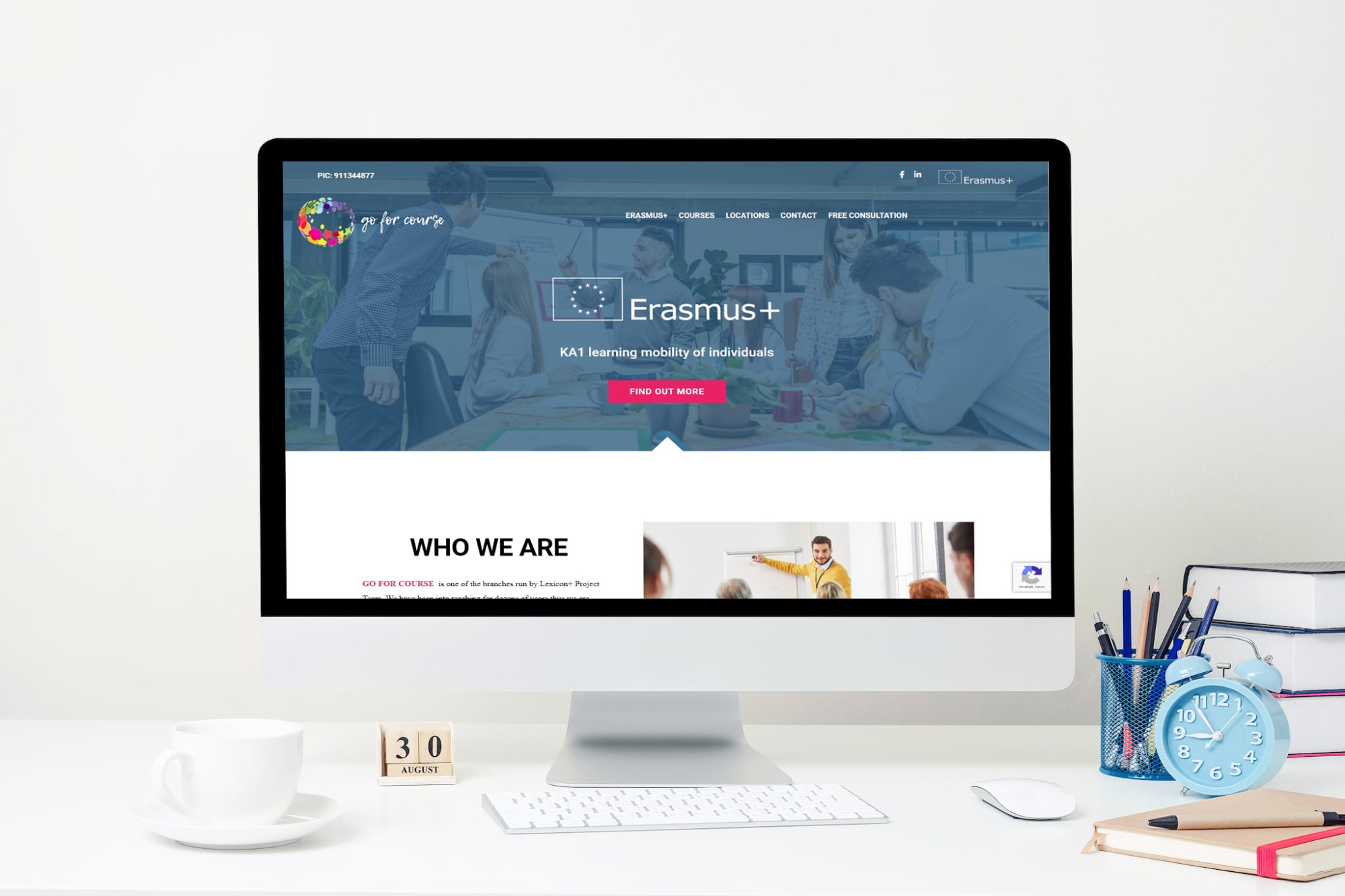 Ekran komputera iMac wyświetlający stronę internetową Goforcourse, platformę kursów online, z elementami interfejsu użytkownika i logo, na białym biurku z akcesoriami biurowymi: kubek, kalendarz...