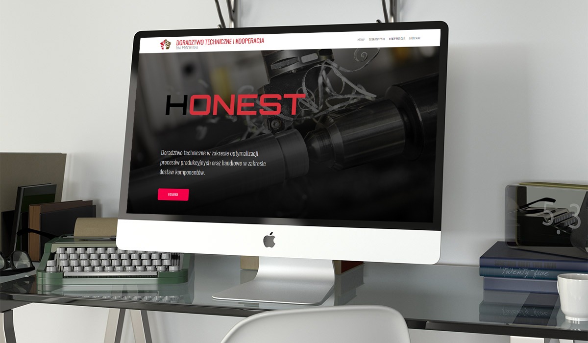 Ekran komputera iMac prezentuje stronę internetową firmy Honest z branży doradztwa technicznego dla przemysłu, widoczny fragment obrabiarki CNC w tle, na biurku obok leżą książki, okulary...