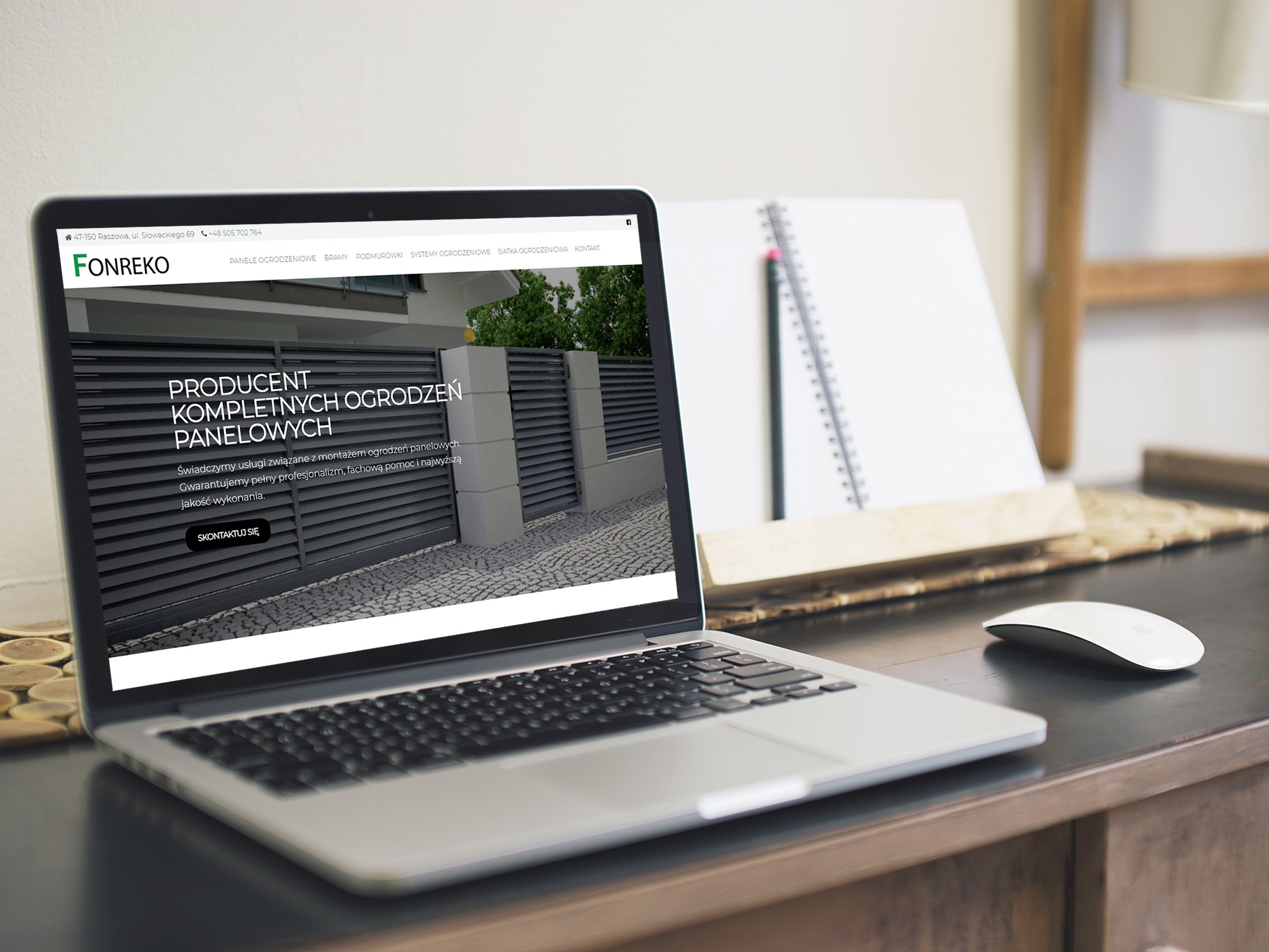 Laptop wyświetla stronę internetową firmy Fonreko prezentującą ogrodzenia panelowe, obok leży notatnik i myszka na drewnianym biurku.