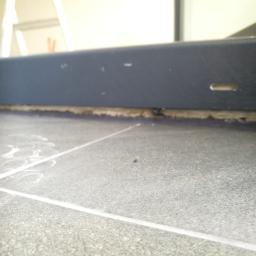 Odbierajznami - Szare płytki podłogowe z fugami, widoczna listwa przypodłogowa i ślady po czyszczeniu