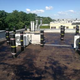 Odbierajznami - Wykonanie hydroizolacji dachu płaskiego z papy termozgrzewalnej, widoczne kominy wentylacyjne, klimatyzatory i zabezpieczone rury na dachu budynku.