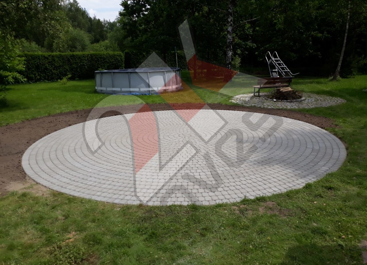 Okrągły taras z jasnoszarej kostki brukowej ułożonej koncentrycznie, przygotowany pod basen ogrodowy, widoczny basen stelażowy, obok miejsce na ognisko z ławką i schodkami.