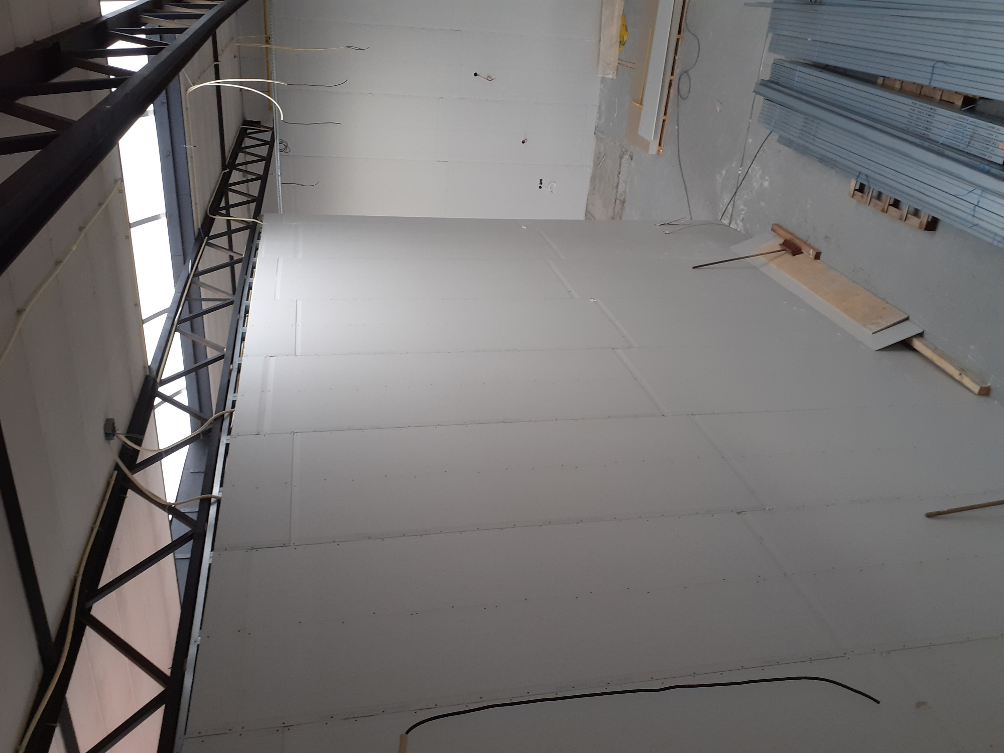 Montaż płyt gipsowo-kartonowych na ścianie w trakcie remontu, widoczne profile konstrukcyjne i instalacje elektryczne.