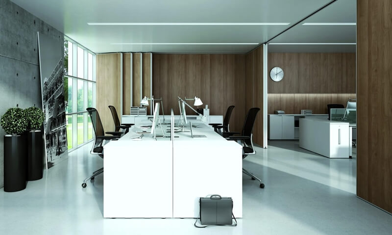 Nowoczesne biuro z białymi biurkami, ergonomiczne krzesła, drewniane panele ścienne i betonowa ściana z dużym zdjęciem, uzupełnione roślinami w czarnych donicach i aktówką leżącą pod biurkiem.