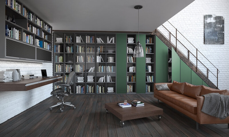 Nowoczesny salon z dużą biblioteczką zabudowaną pod schodami, biurkiem z laptopem i skórzaną sofą, oświetlony wiszącą lampą.