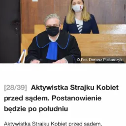 Sędzia w todze i maseczce siedzi na sali sądowej, za nim kobieta w maseczce. W tle drewniane panele.